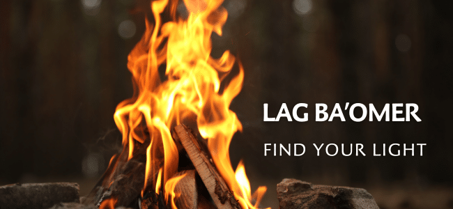 A bright bonfire burns outdoors with the words "LAG BA’OMER" and "FIND YOUR LIGHT" written beside the flames. The background is blurred, highlighting the fire.