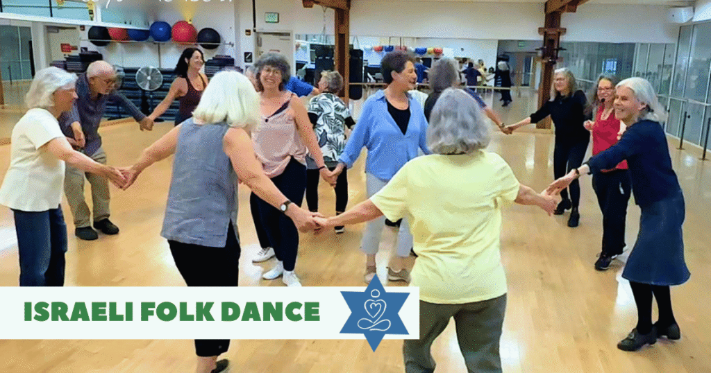 A group of people holding hands and dancing in a circle in a gym studio. Text reads "Israeli Folk Dance" with a blue star and yoga icon.