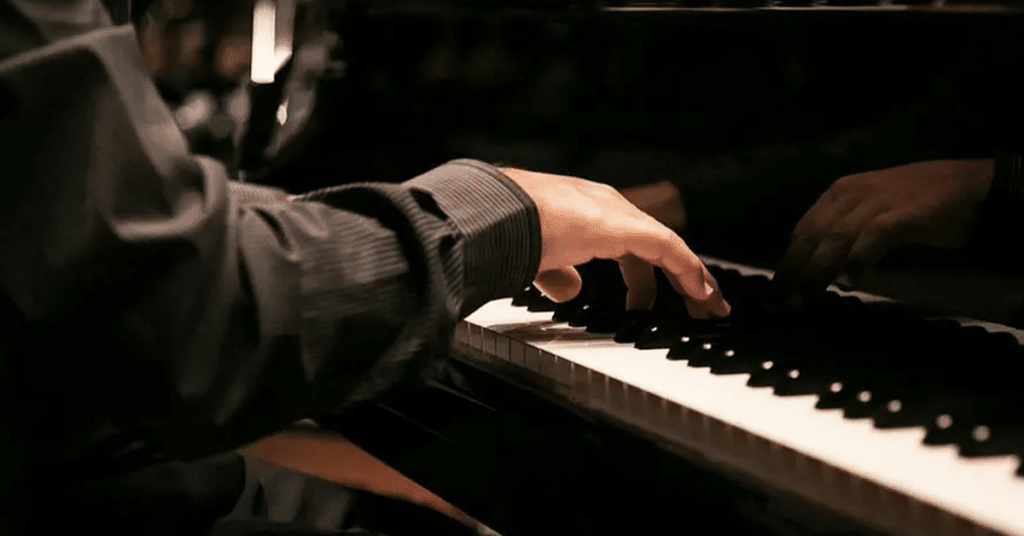 A pianist’s hands playing a grand piano.
